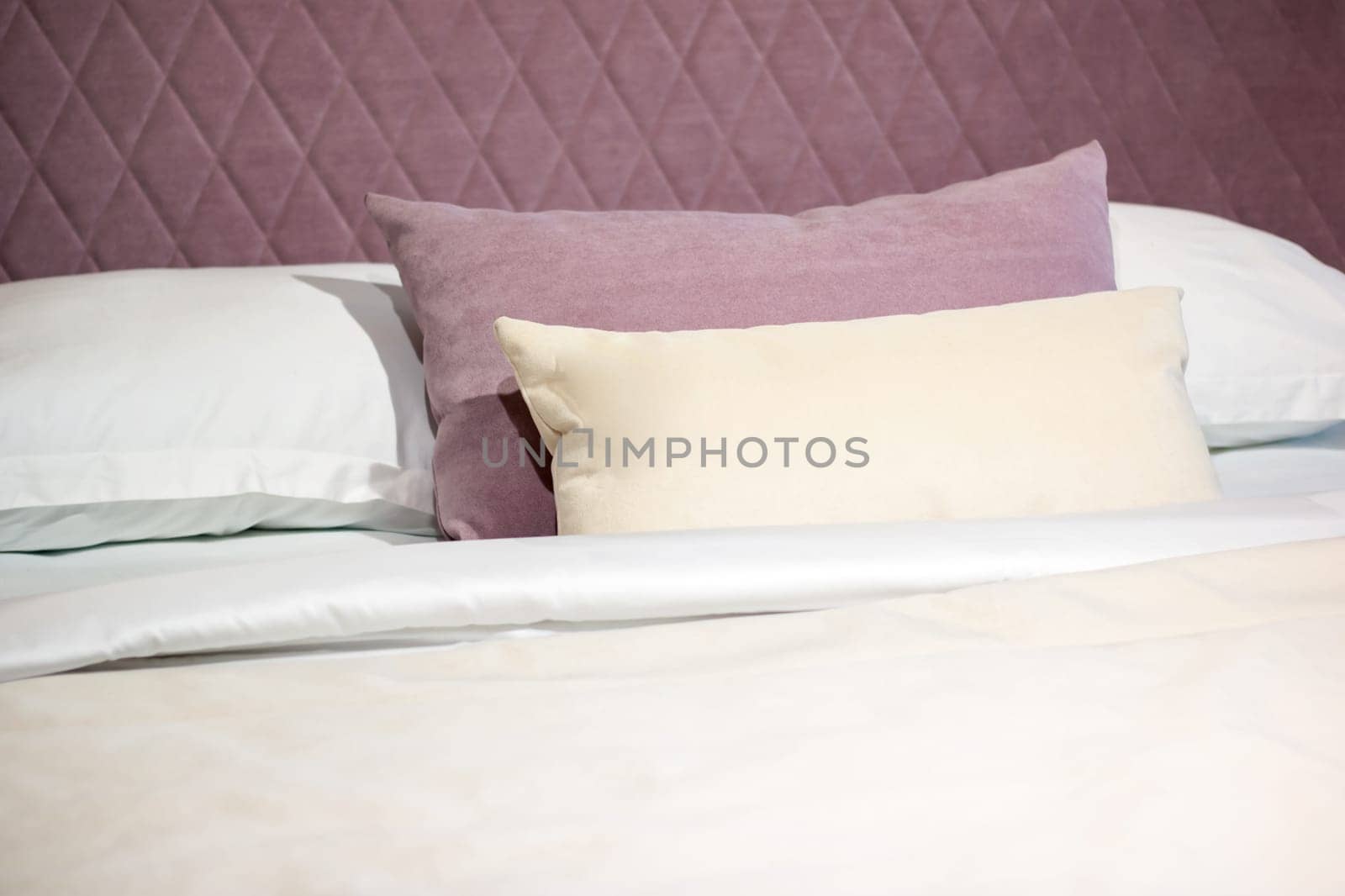 Soft pillows on a large bed in pastel colors by Vera1703