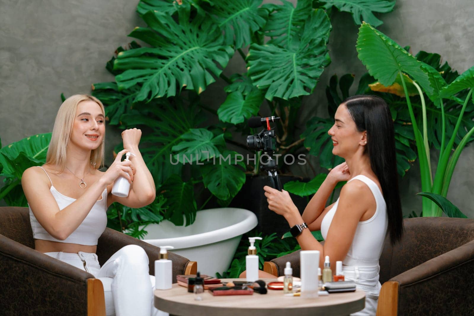 Two beautiful content creator making natural beauty and cosmetic tutorial on green plant garden video. Beauty blogger showing how to beauty care to social medial audience using selfie stick . Blithe