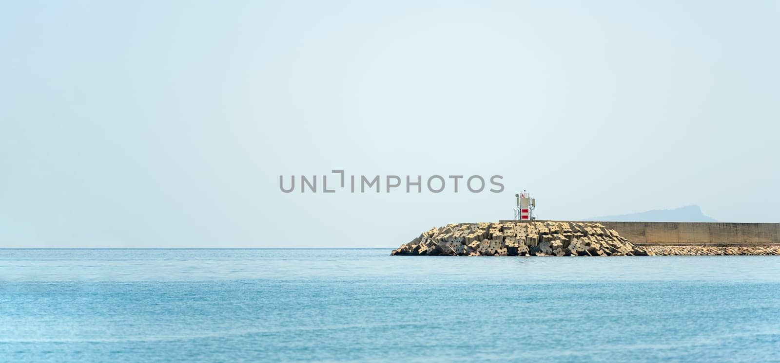 Breakwater and lighthouse at the entrance of the fishing harbor in Antalya Turkey by Sonat