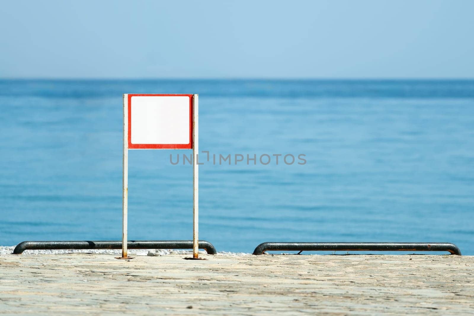 Blank warning sign by the sea on a sunny clear summer day by Sonat