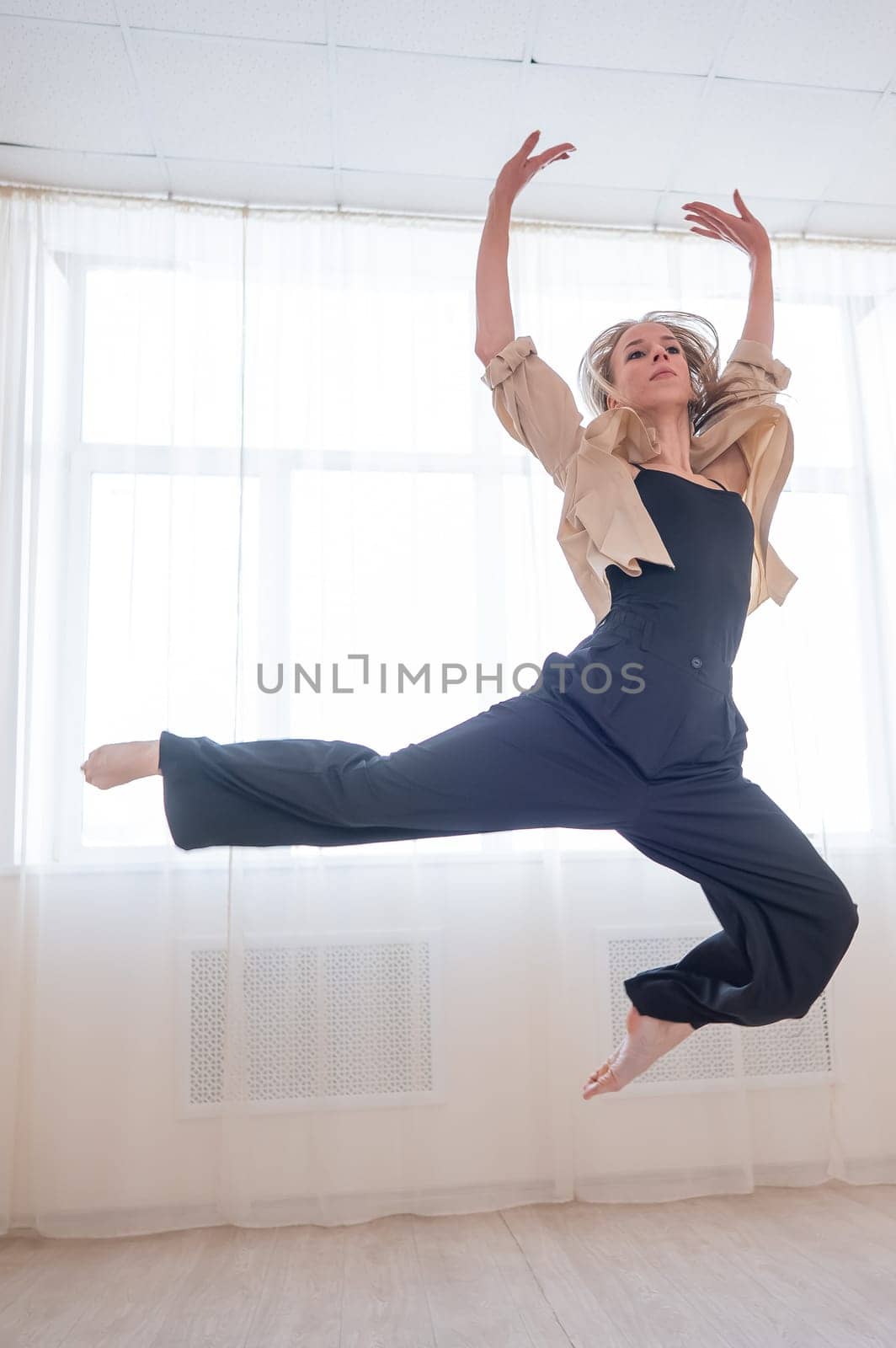 Caucasian woman dances contemporary in ballet class. Dancer in a jump. Vertical photo. by mrwed54