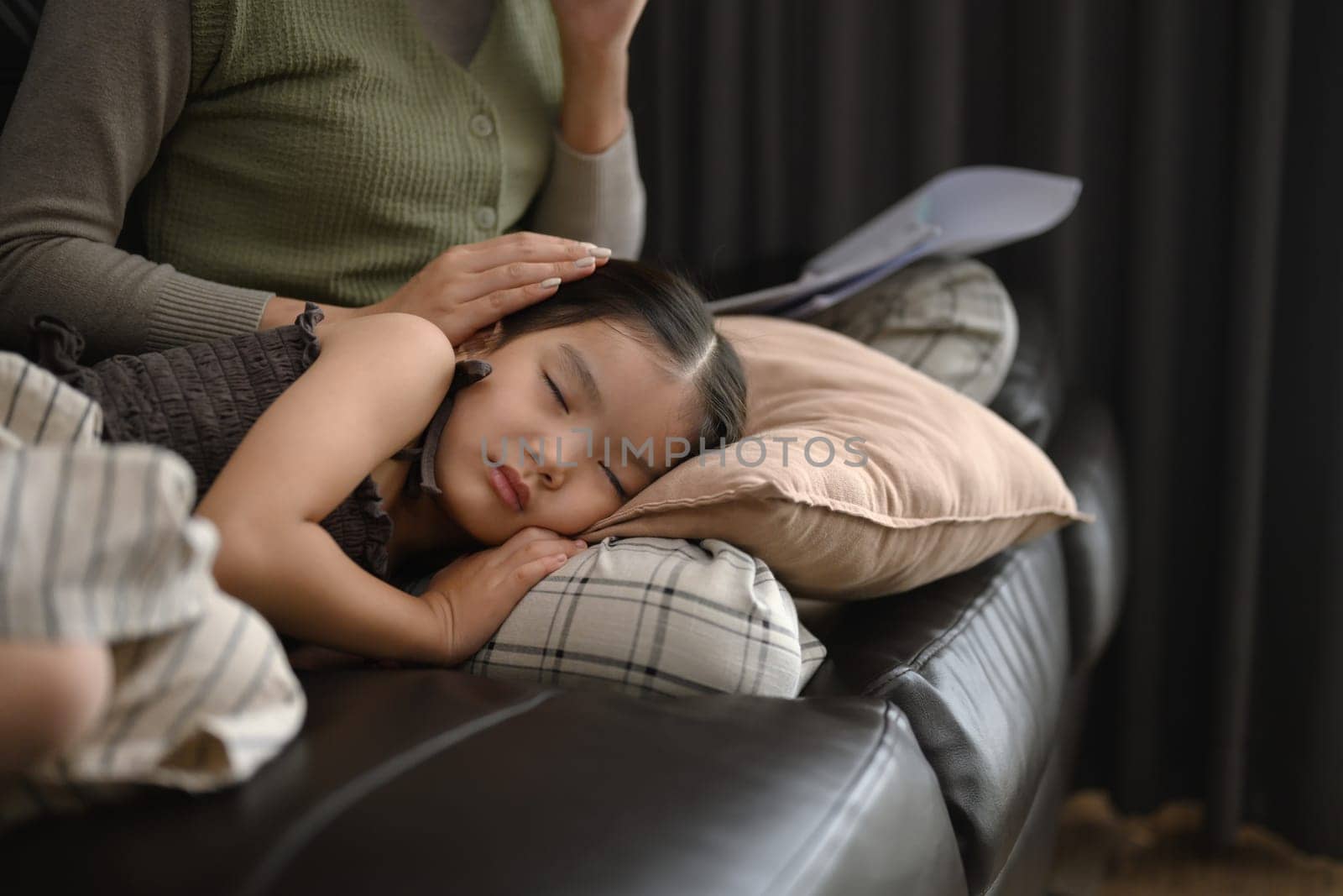 Cute little girl sleeping peacefully on sofa in her working mother.