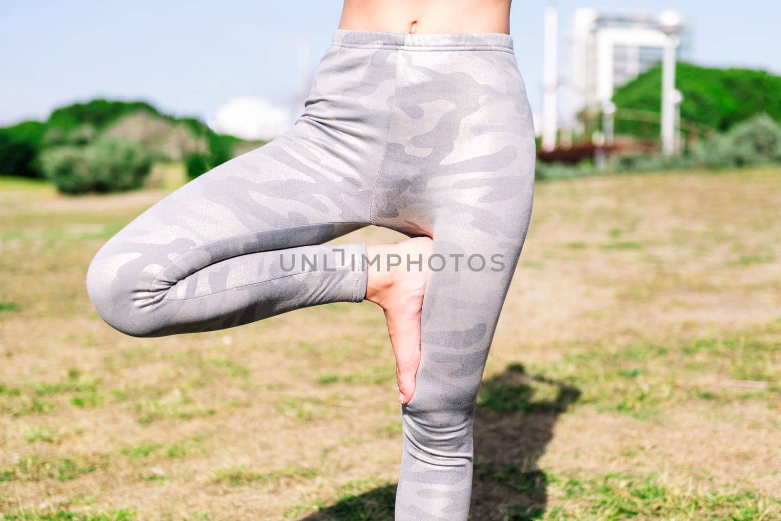 close up detail of an unrecognizable woman doing yoga positions at park, active and healthy lifestyle concept