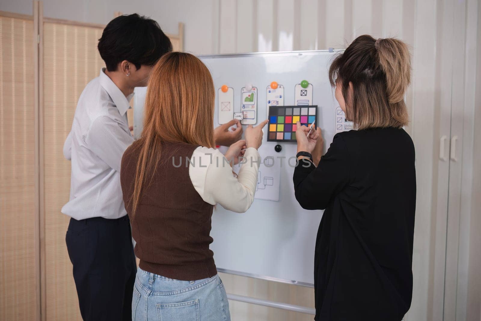 A team of software developers brainstormed to design a smartphone application by planning on a whiteboard and using it to develop the application system..