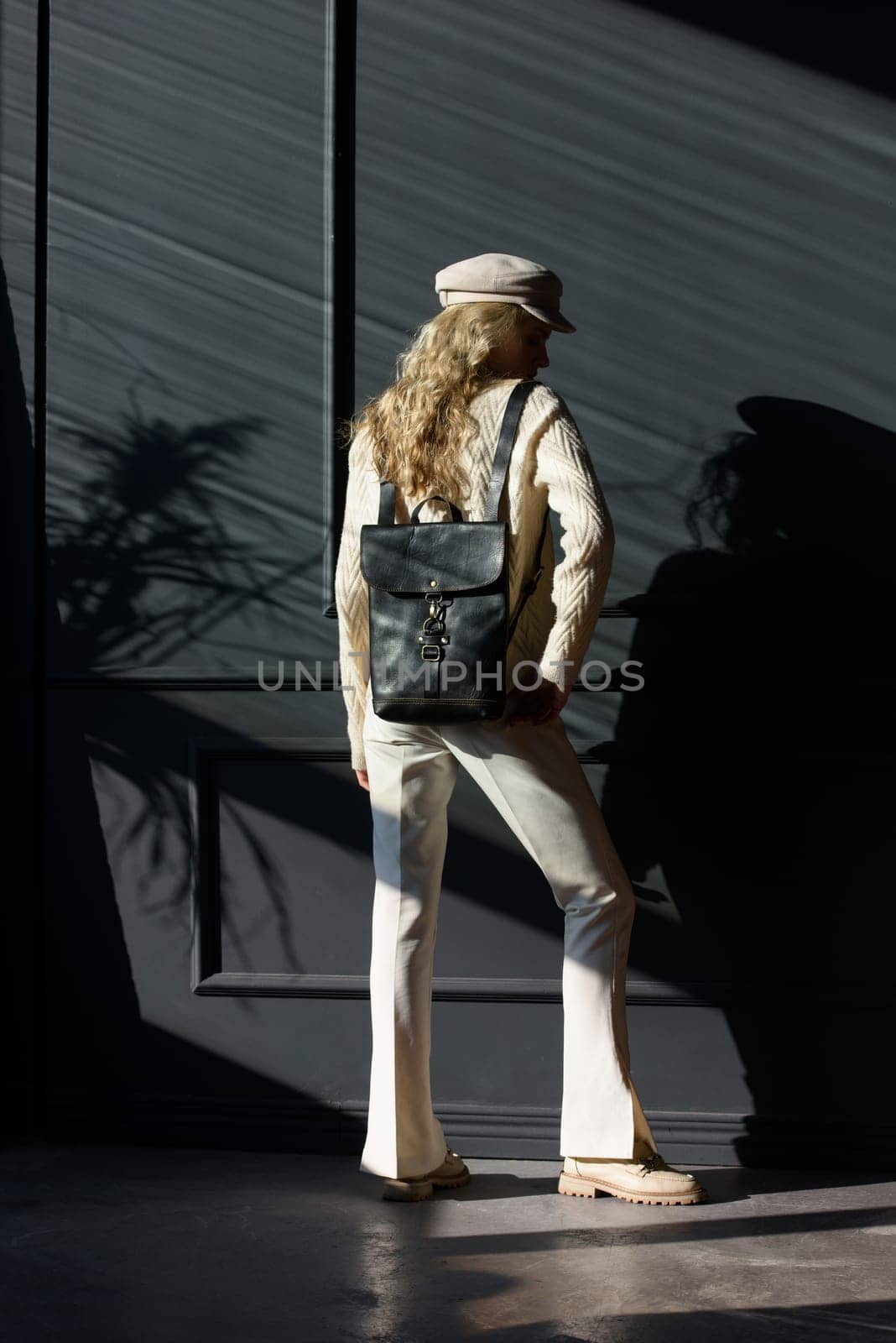 Studio portrait of beautiful woman with a curly blond hair holding brown bag, posing on gray background. by Ashtray25