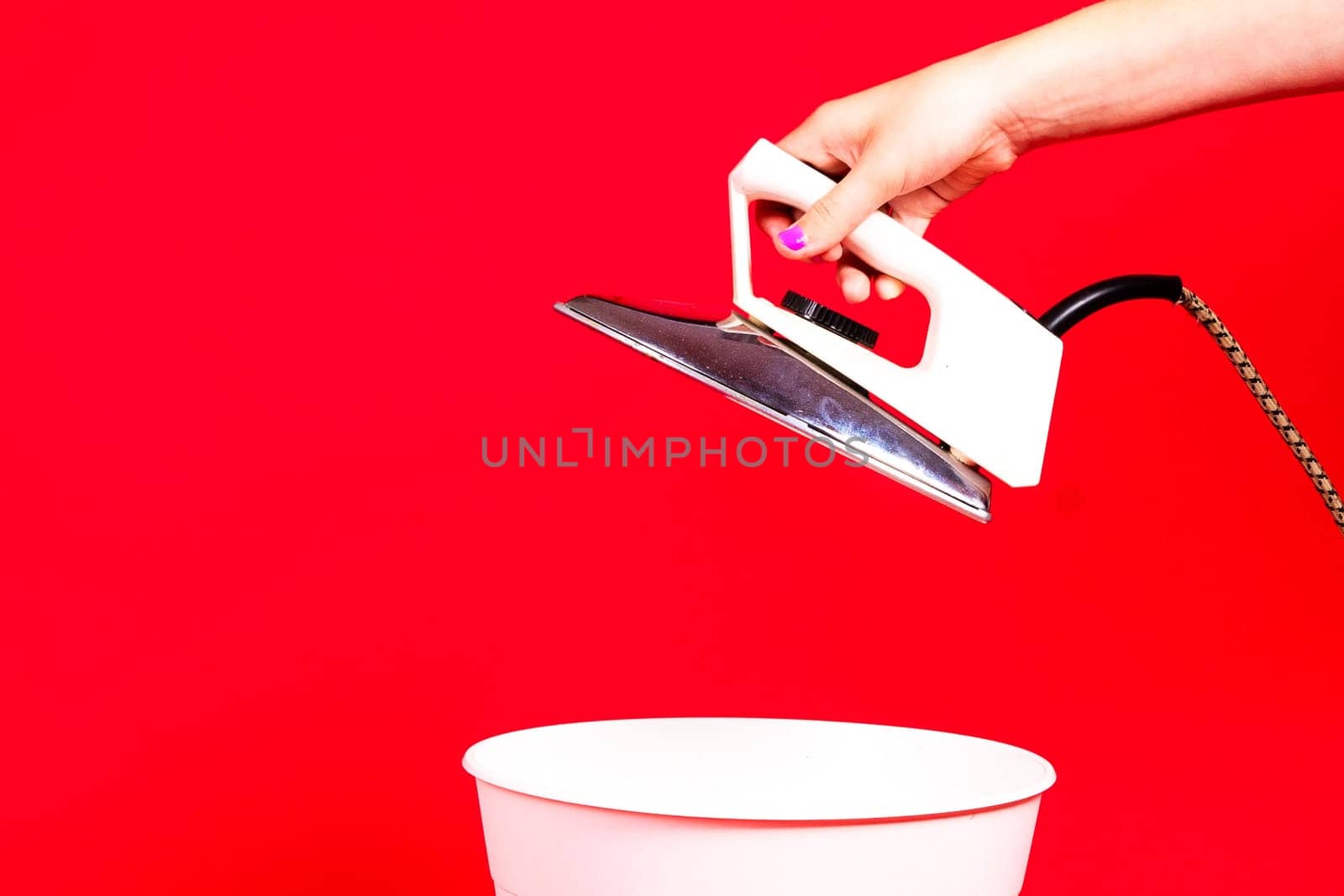 Woman putting iron in recycle bin on red background by Zelenin