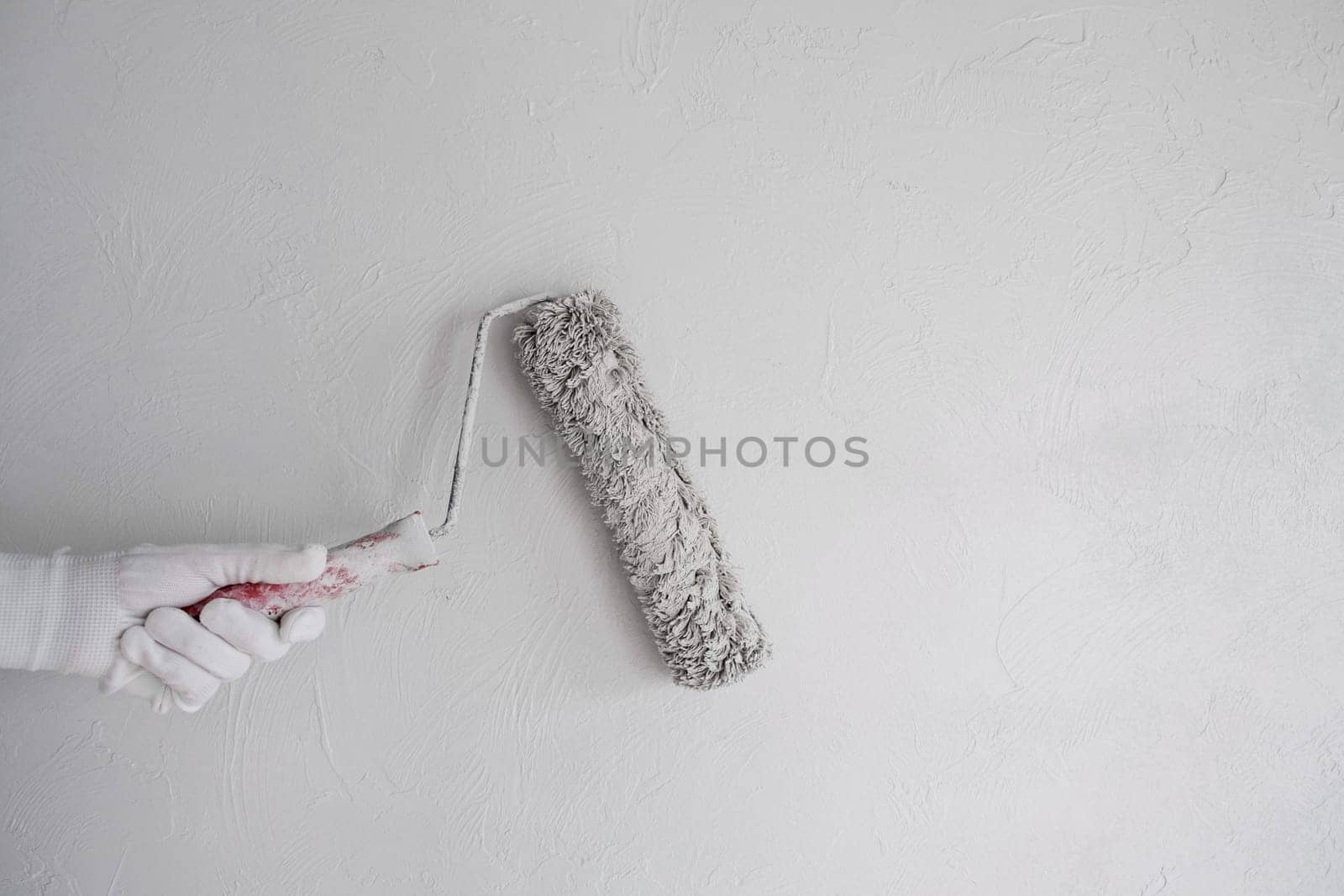 Painting a bare wall with a roller with white paint. Apartment painting by AnatoliiFoto