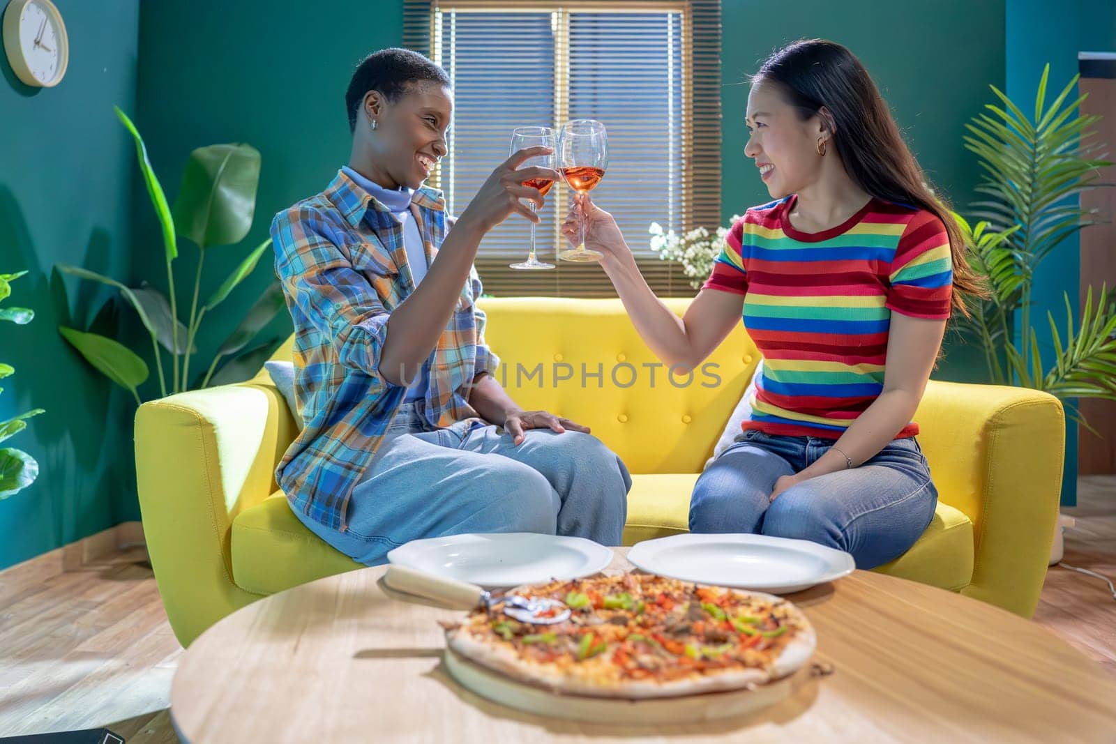 Two best friends toasting Celebrating With Glass Of Wine At Home Together raising wineglasses. High quality photo