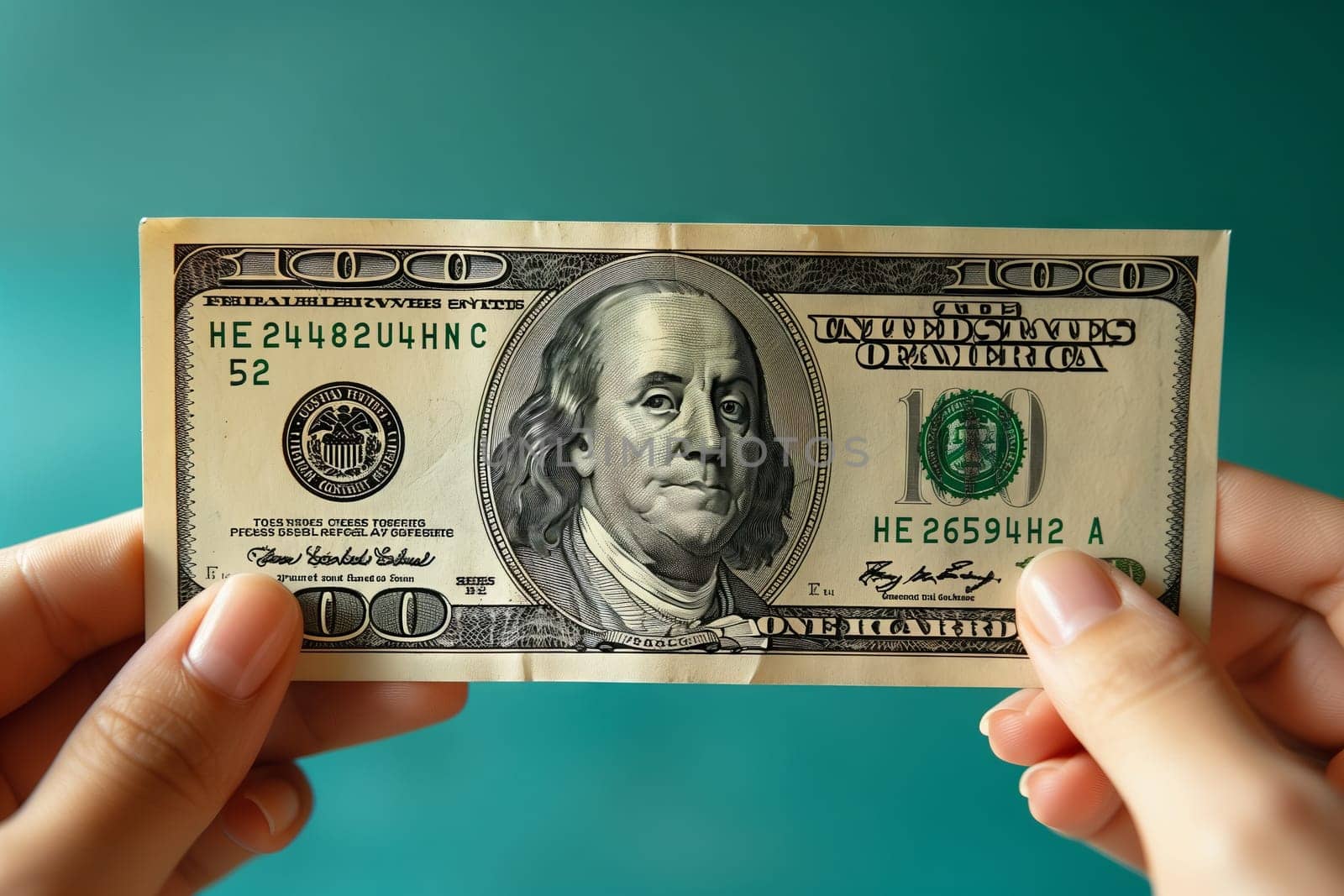 The person is holding a 100 dollar banknote in their hand, carefully handling the money with their fingers and thumb. The signature on the cash is clearly visible