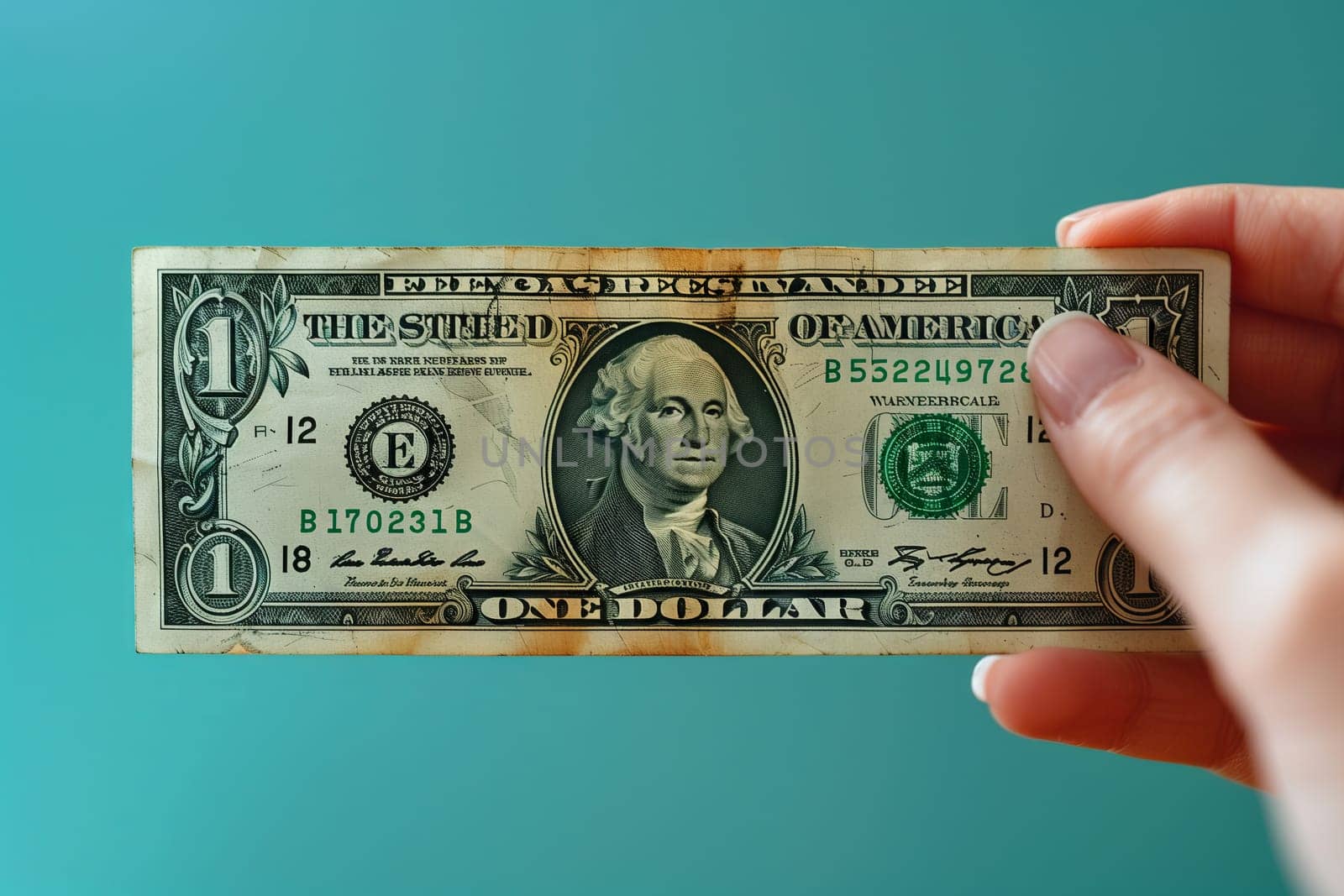 The person is holding a rectangular banknote with their thumb and finger, examining the intricate font and line details on the one dollar bill