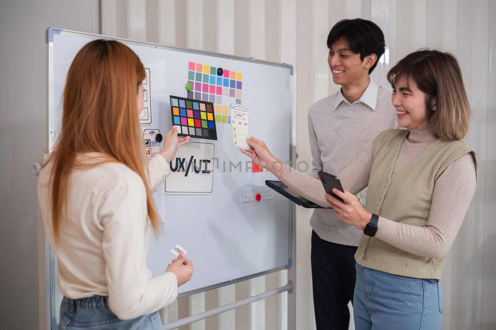 A team of software developers brainstormed to design a smartphone application by planning on a whiteboard and using it to develop the application system. by wichayada