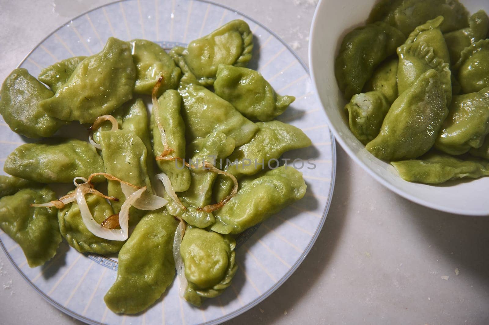 Served plates with freshly prepared dumplings with mashed potatoes, on a marble table background. Culinary. Homemade cooking. Food background. Ukrainian or Italian traditional meal. View from above