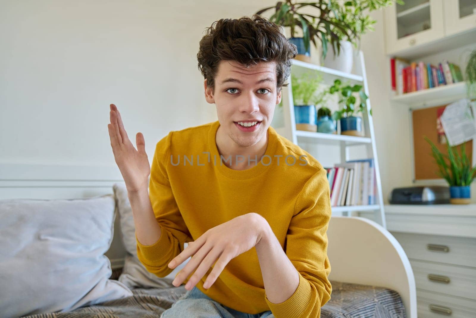 Web camera view of young guy 19-20 years old talking looking at camera in home by VH-studio