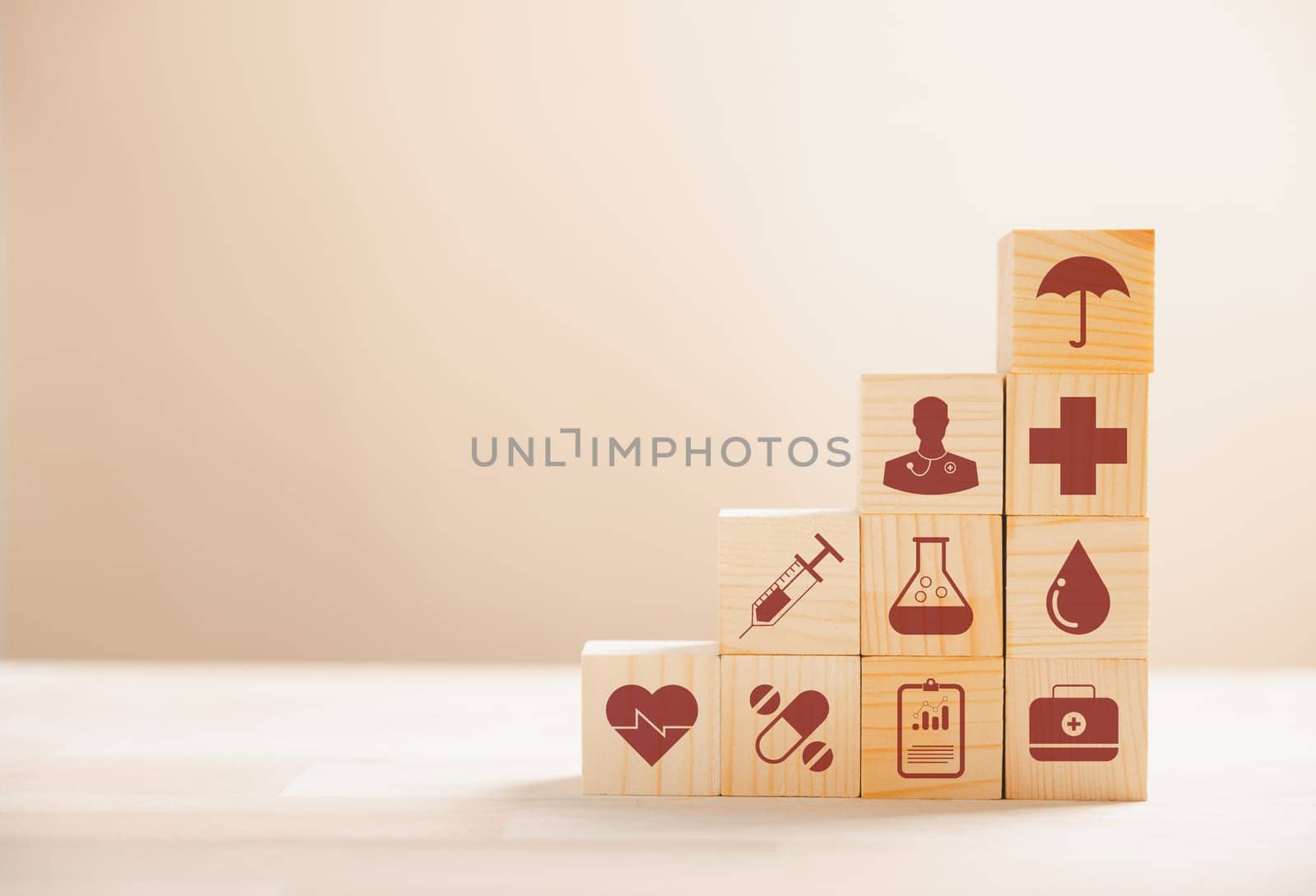 Wooden cubes stacked in a pyramid shape, embodying the healthcare and insurance concept. Atop, a medical insurance icon signifies protection. Blue background offers copyspace for Health Insurance idea