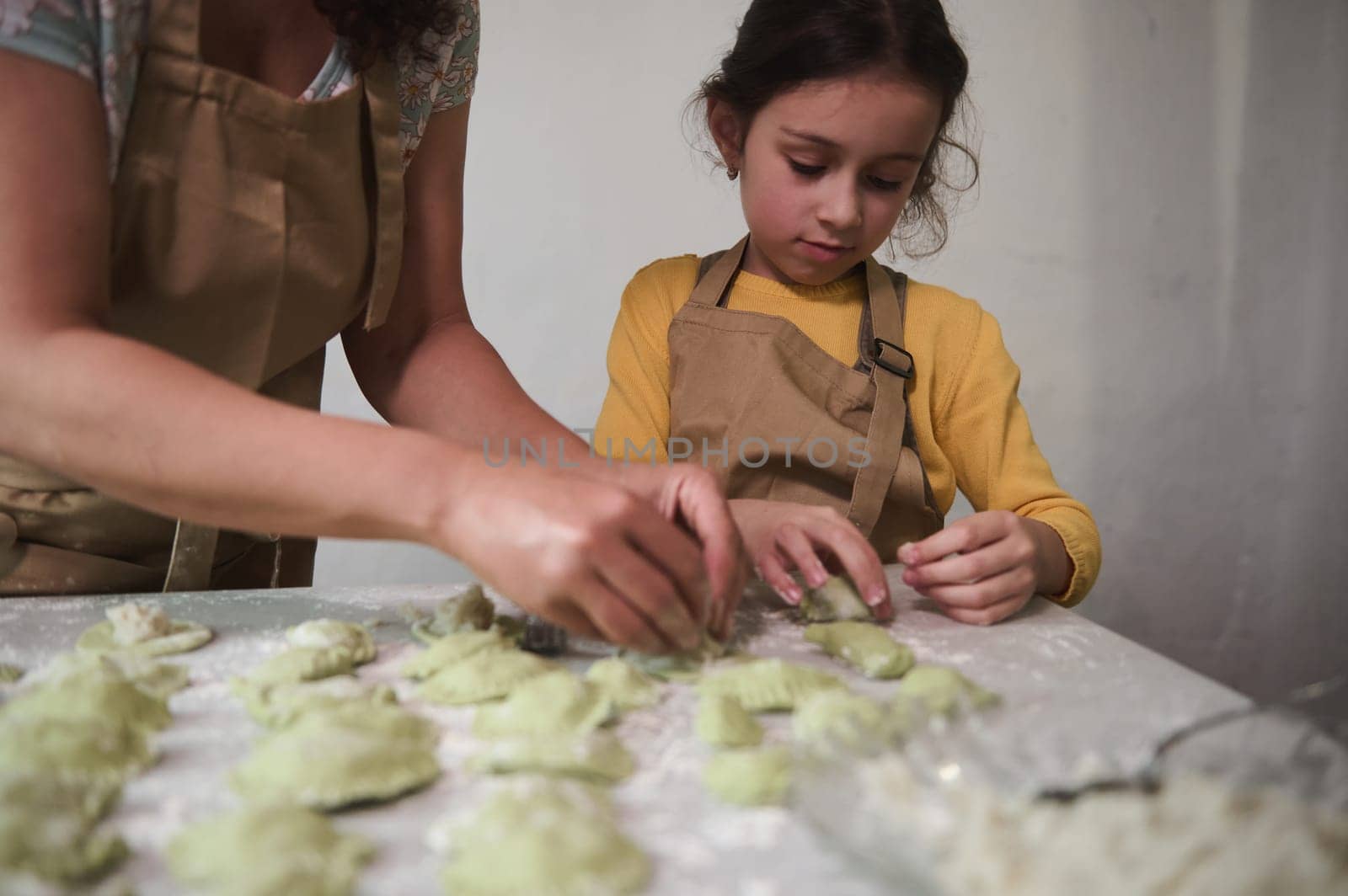 Mother and daughter cooking together varennyky for family dinner, stuffing dough with mashed potatoes and molding dumpling, preparing meal according to traditional recipe, in the rustic kitchen