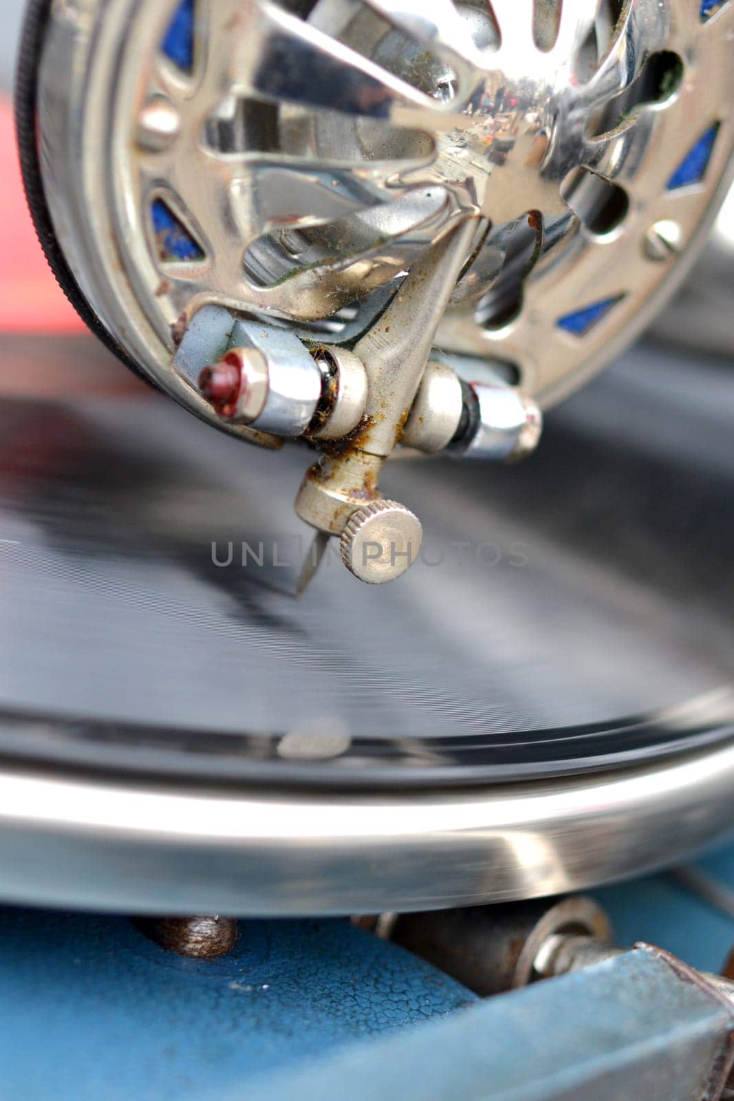 An old retro record playing on old vintage gramophone at flea market. Work of portable gramophone. Old vintage shabby record player, phonograph, potefone. Needle close up. Nostalgia antique turntable