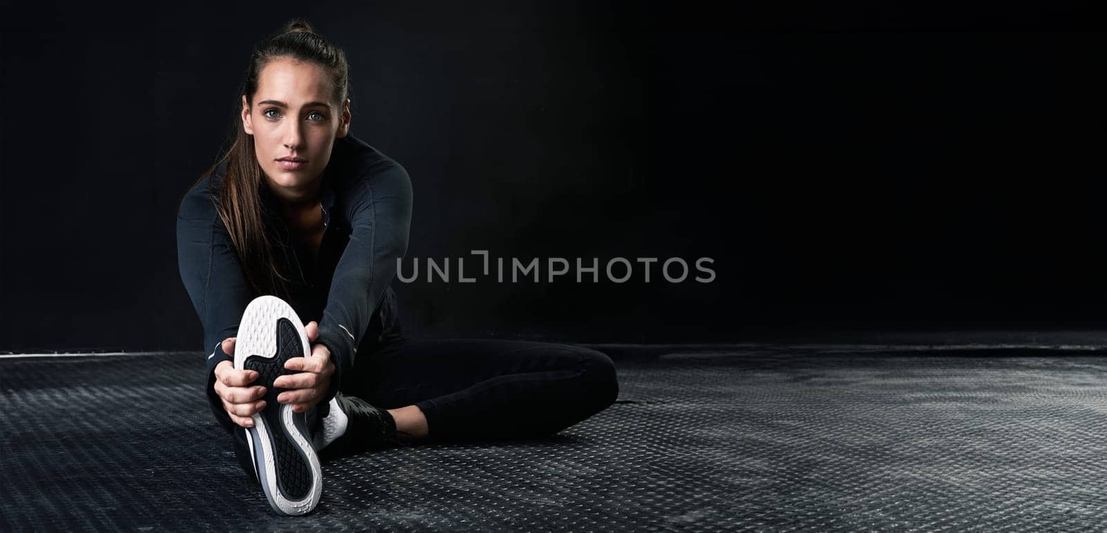 Portrait, fitness and stretching with sports woman on space for start of health or workout routine. Exercise, floor and warm up with confident young athlete training in studio to improve performance by YuriArcurs