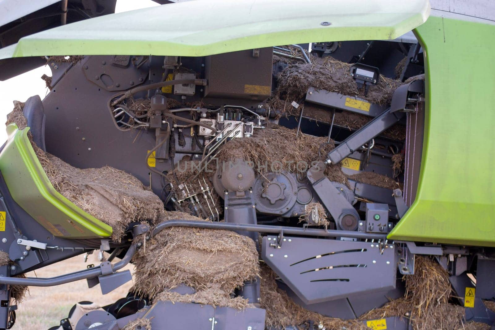 Tractor combine for straw baling inside clogged with debris dirt dust straw hay soil. Mechanism structure details