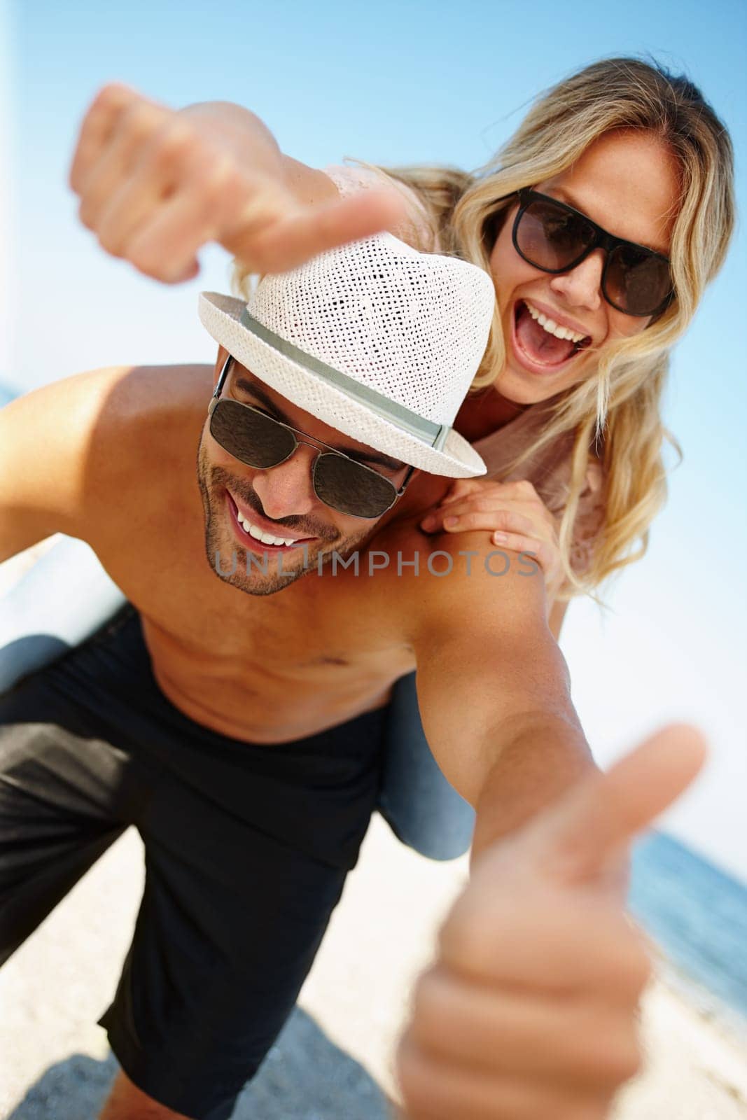 Couple, thumbs up and portrait at beach for travel outdoor, agree for break and relax for relationship. Boyfriend, girlfriend or tourist and showing yes sign and smile by ocean for summer holiday.