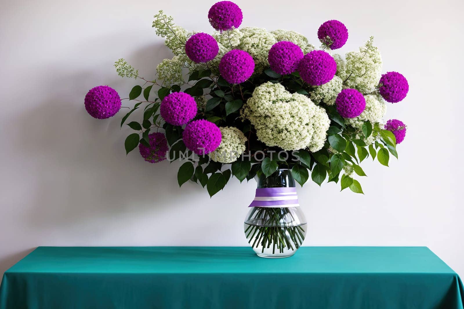 The image shows a vase filled with pink and white flowers on a blue tablecloth.