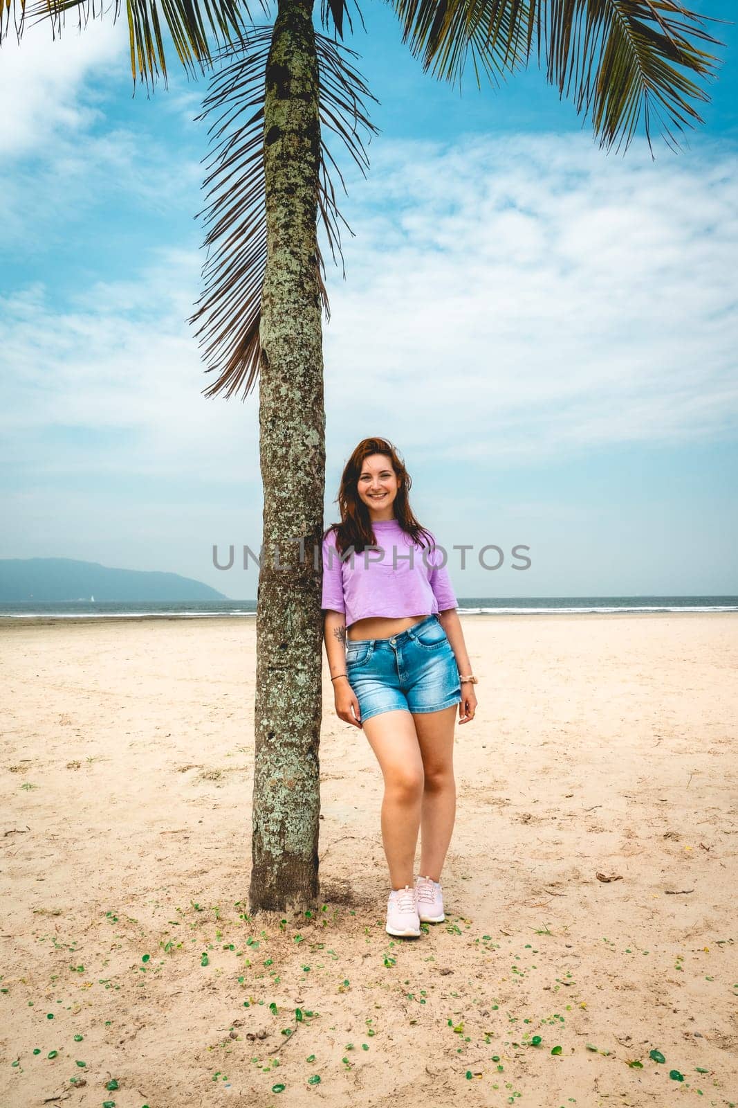 Brazilian Woman posing at a palmtree at the beach of Santos, Brazil.
