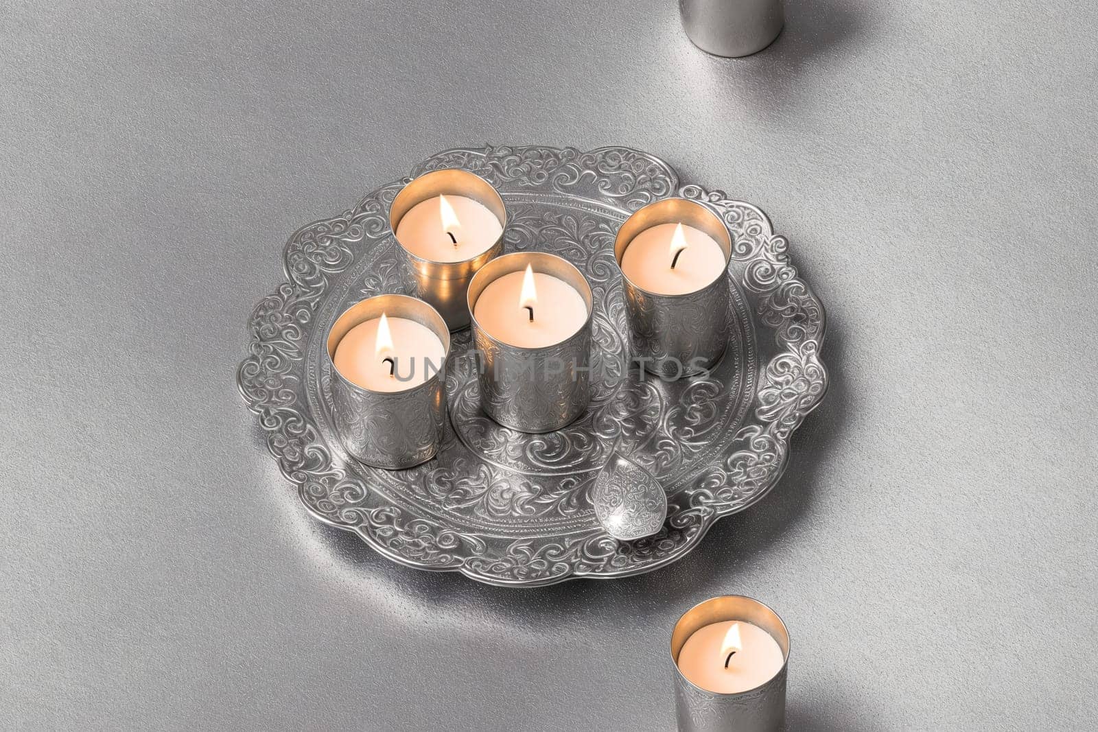 The image shows a silver tray with three white candles on it.