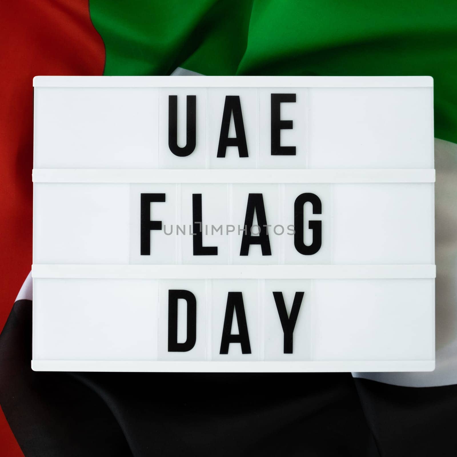 Message with text UAE FLAG DAY on United Arab Emirates waving flag made from silk material. Independence Commemoration Day Muslim Public holiday celebration background. The National Flag of UAE. Patriotism