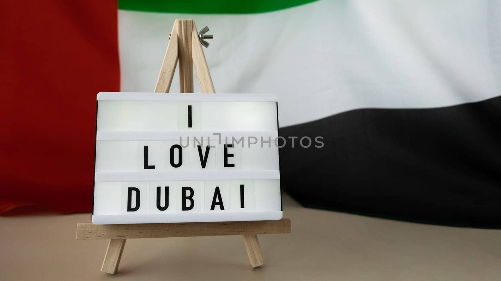 Message text I LOVE DUBAI on background of waving UAE flag made from silk. United Arab Emirates flag with concept of tourism and traveling. Inviting greeting card, advertisement. Dubai welcoming card