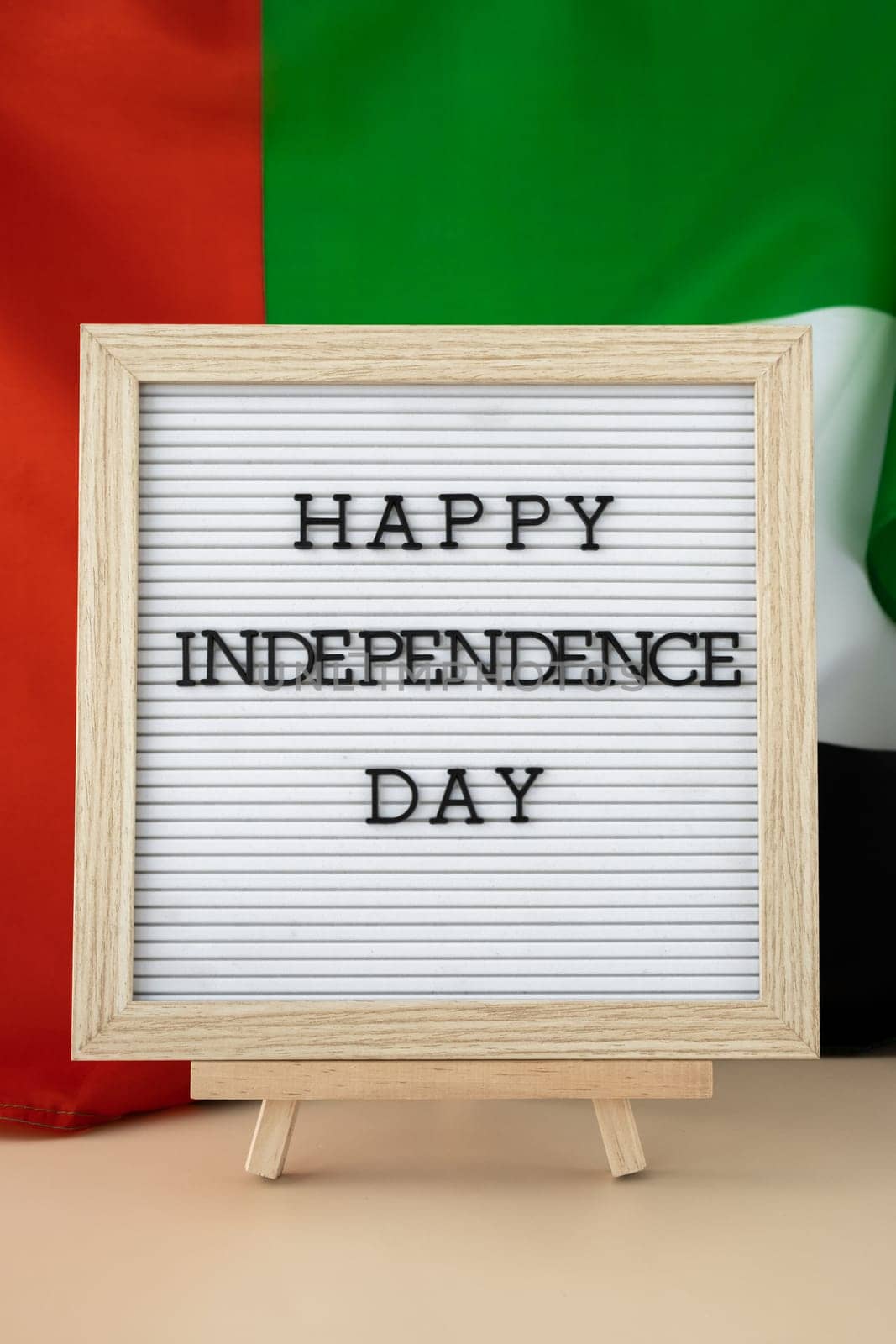 HAPPY INDEPENDENCE DAY text frame on United Arab Emirates waving flag made from silk material. Commemoration Day Muslim Public holiday celebration background. The National Flag of UAE by anna_stasiia