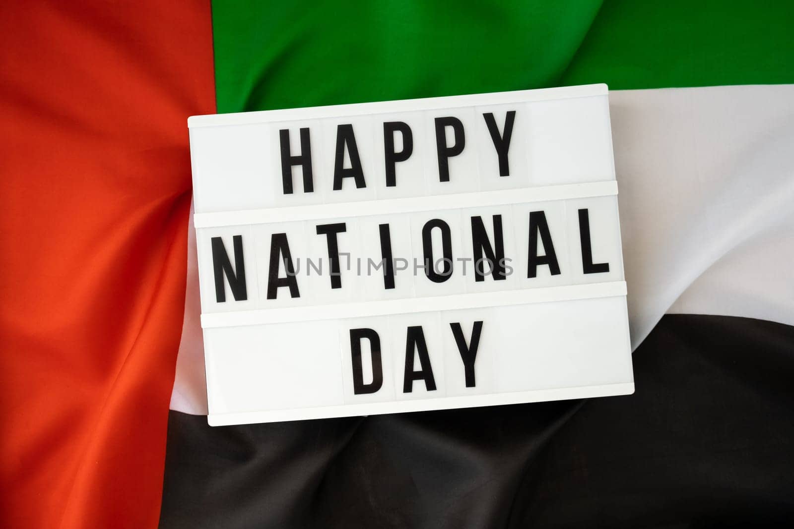 Text HAPPY NATIONAL DAY on background waving flag of UAE. National holiday of United Arab Emirates. Commemoration Day Muslim Arabian holidays. Dubai celebration