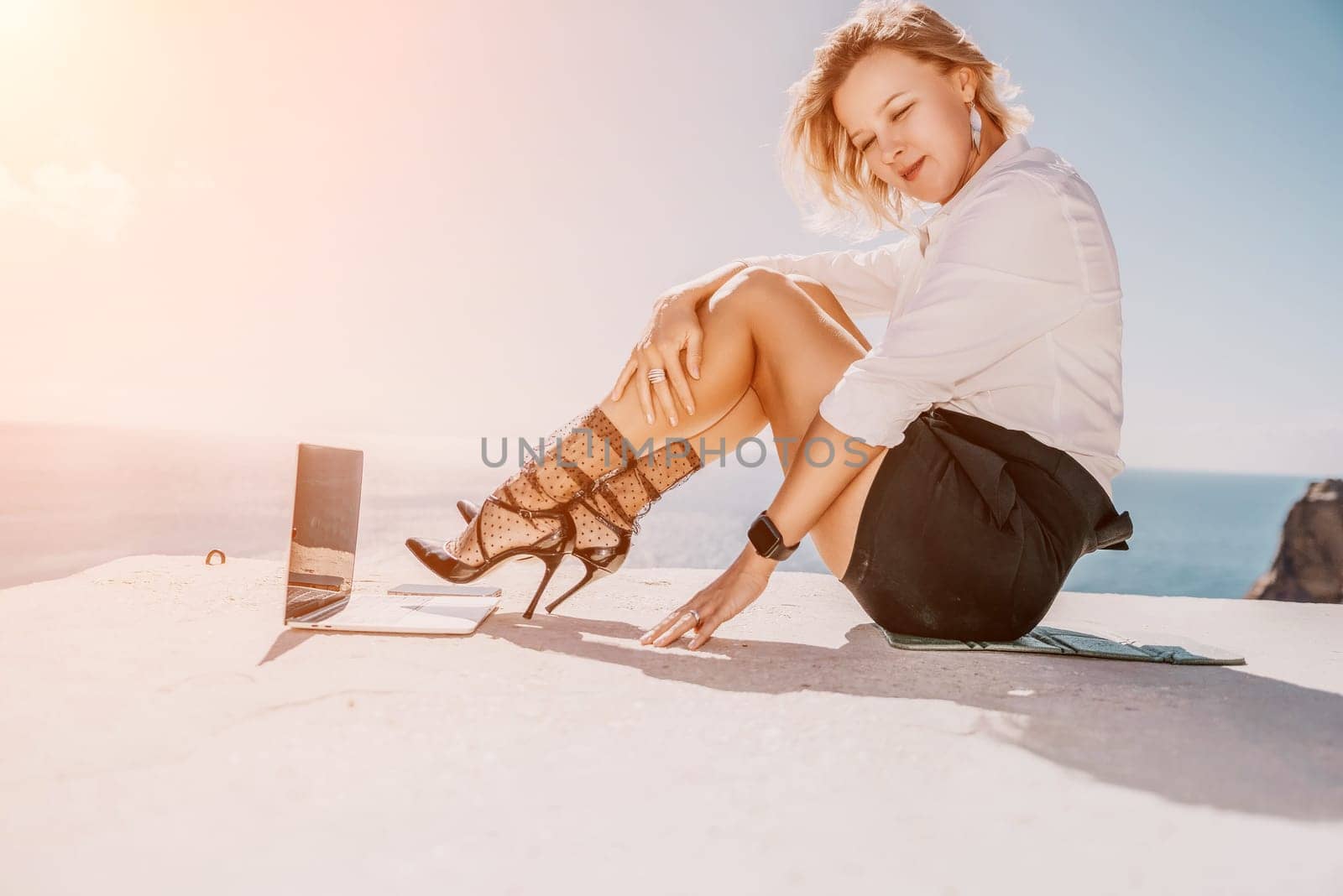 Woman sea laptop. Business woman in yellow hat freelancer with laptop working over blue sea beach. Girl relieves stress from work. Freelance, digital nomad, travel and holidays concept by panophotograph