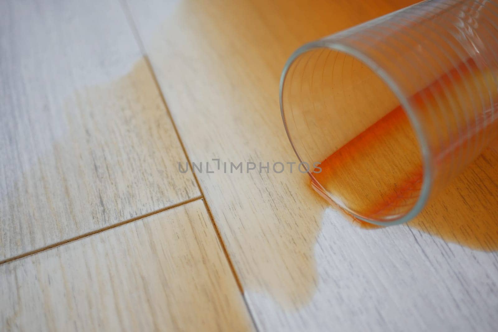 cup of coffee spilled on wooden floor .