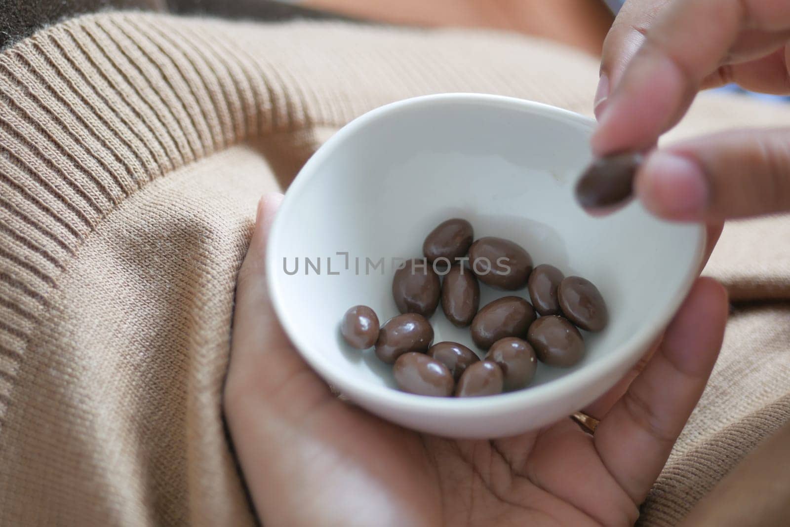 woman hand pick round shape chocolate candy in a bowl by towfiq007