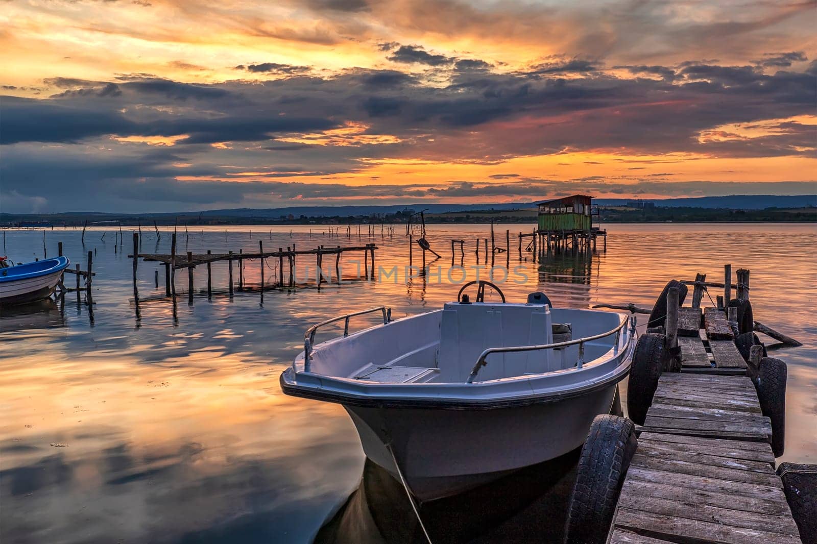 Stunning sunset at sea shore with boat at jetty