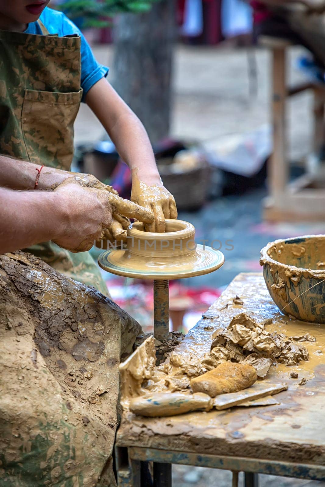 A master of pottery craftsmanship teaches a child who wants to learn how to sculpt a jug. Pottery master class. by EdVal