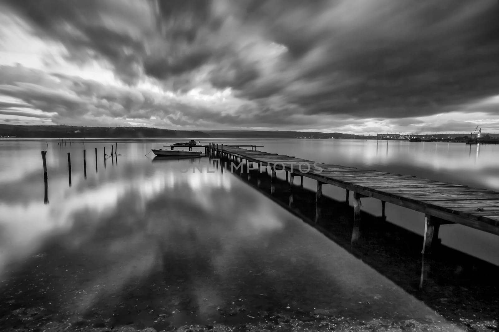 Dramatic Black and white landscape with wooden pier and fishing boat