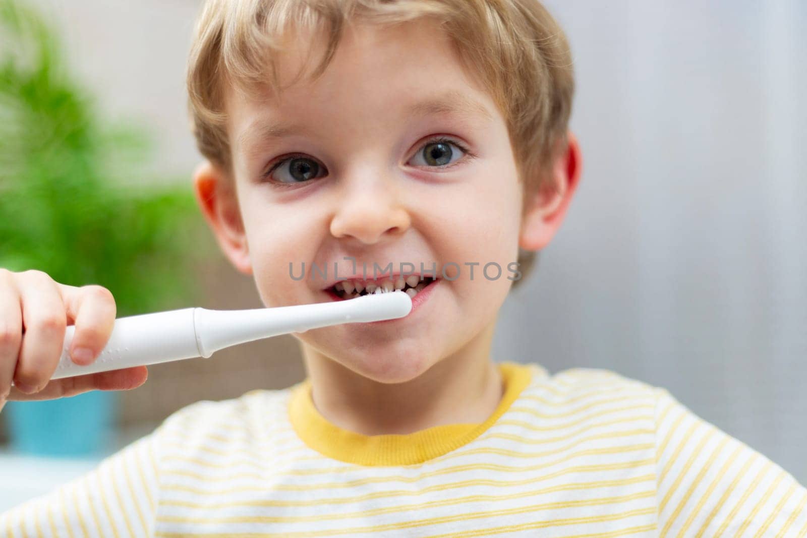 Young boy brushing teeth with electric toothbrush. Oral hygiene routine concept. Portrait with copy space for dental health educational posters and banners.
