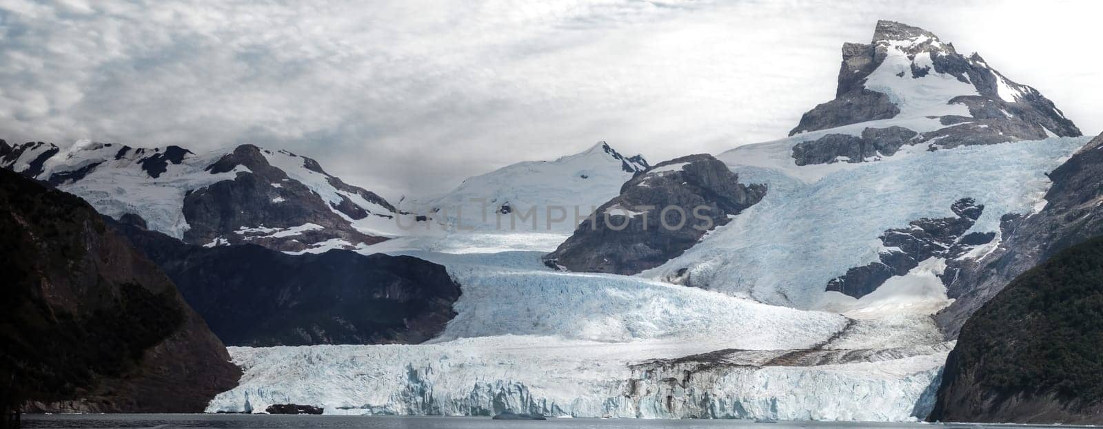 Vast glacier with surrounding snowy peaks and a striking sky.