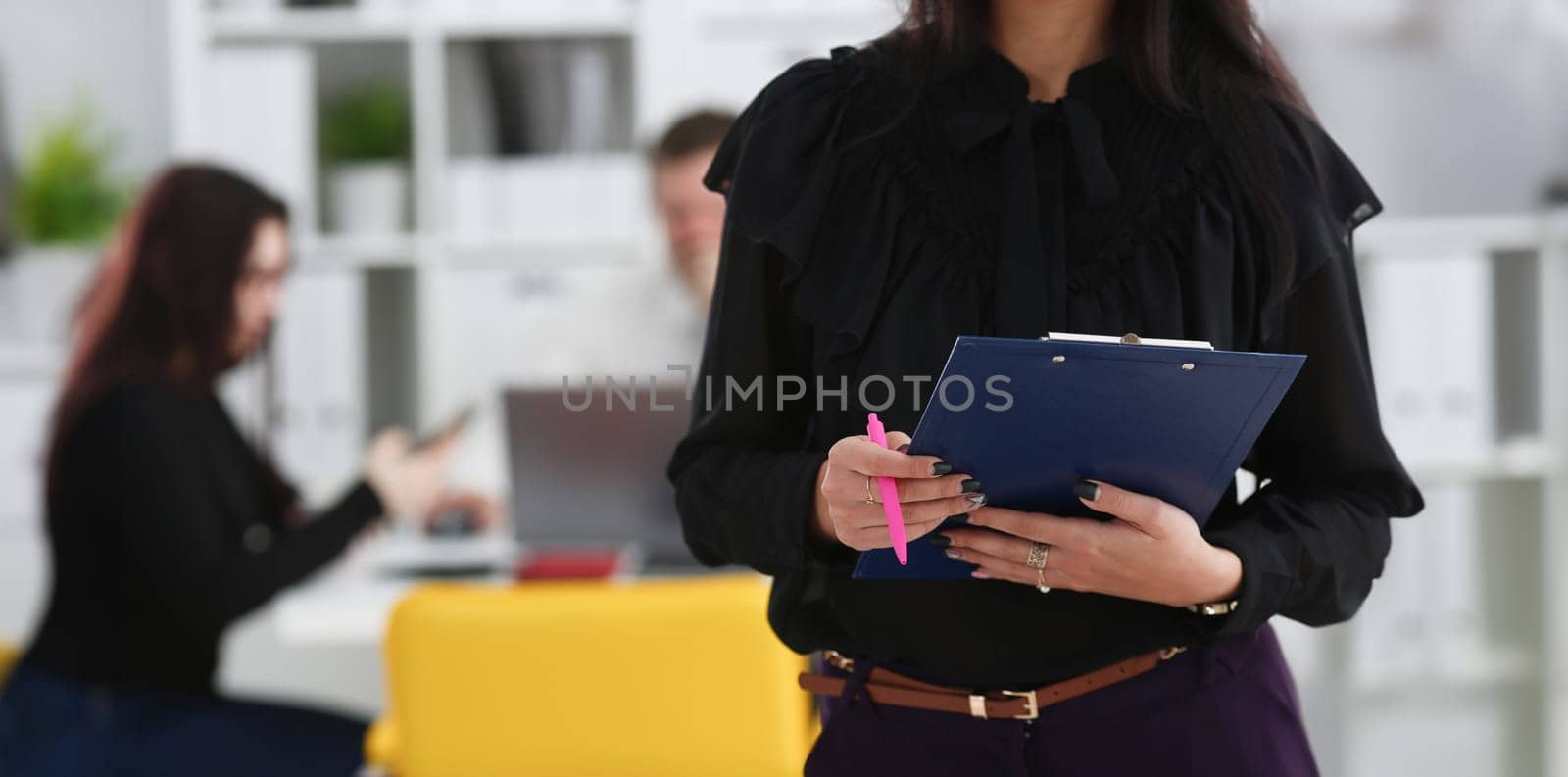 Brunette woman hold in arms pink pen and paper clipped to pad closeup colleagues in background. White collar worker at workspace officer highly pay smart serious headhunter offer