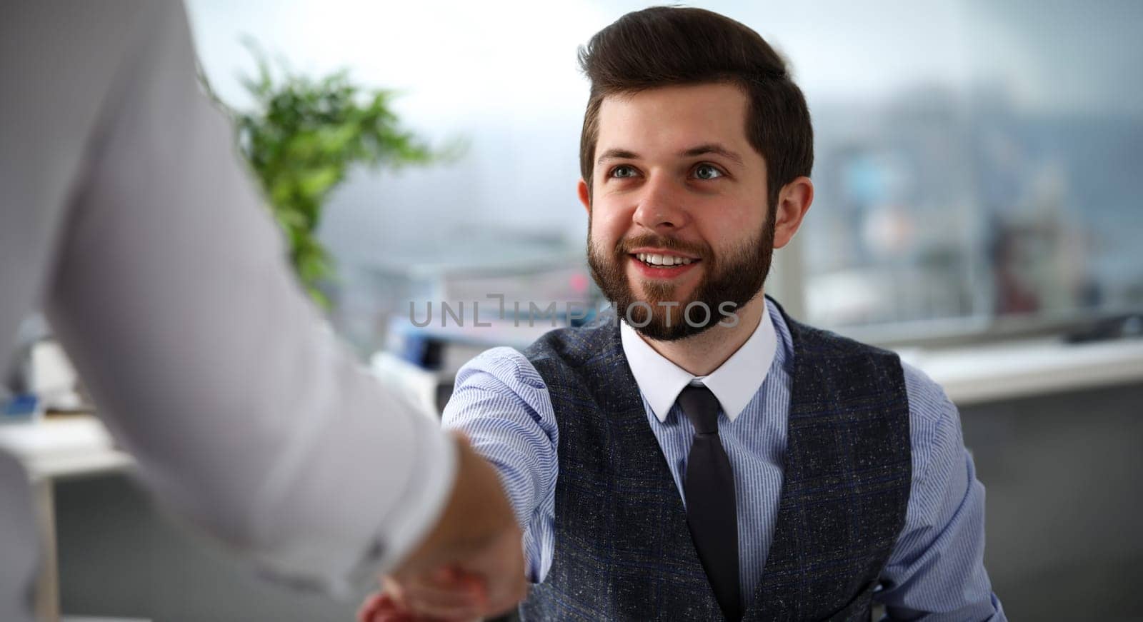 Man in suit and tie give hand as hello in office by kuprevich