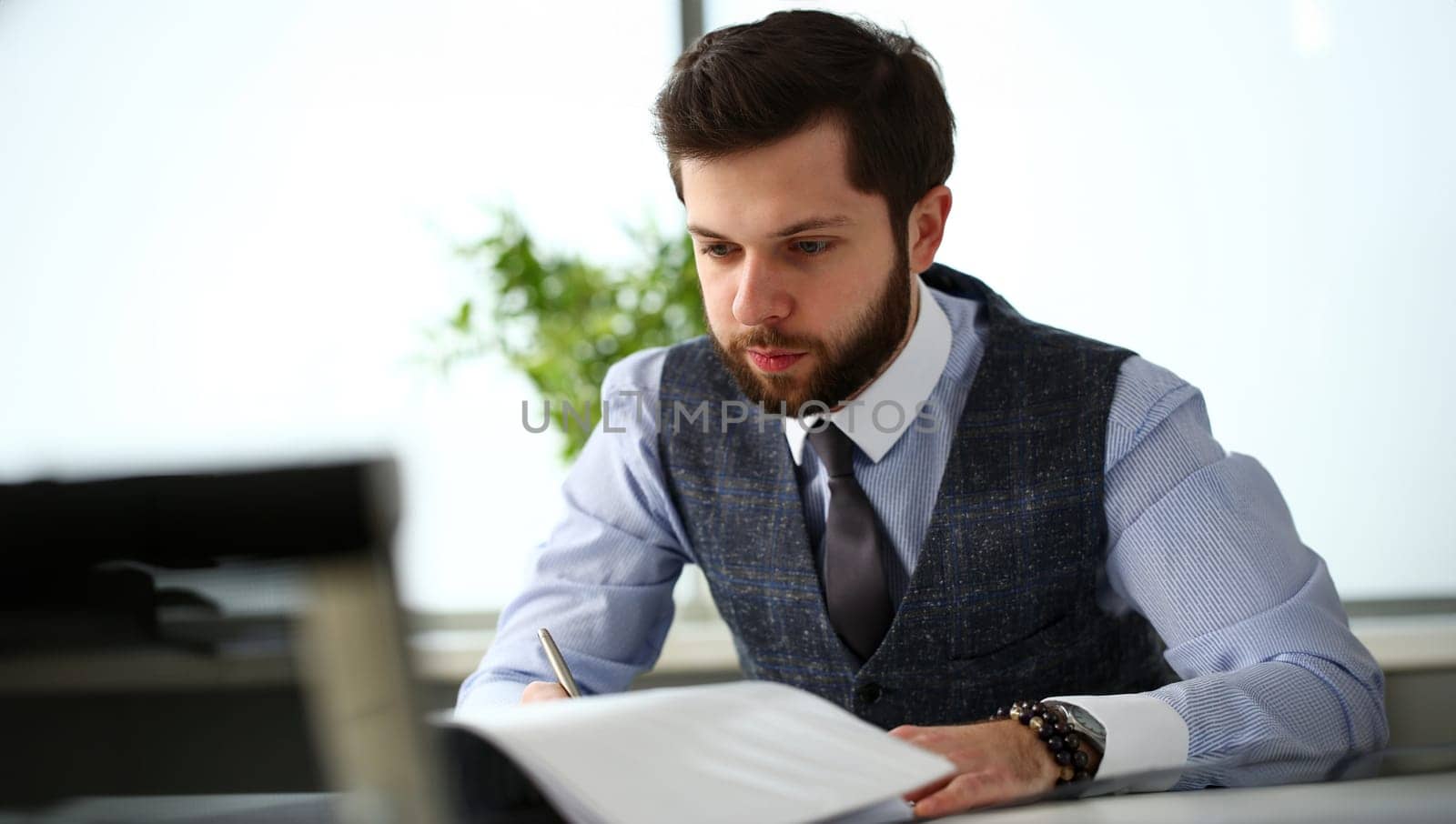 Handsome smiling bearded clerk man at office workplace with silver pen in arms do paperwork portrait. Staff dress code worker job offer client visit study profession boss market idea coach training