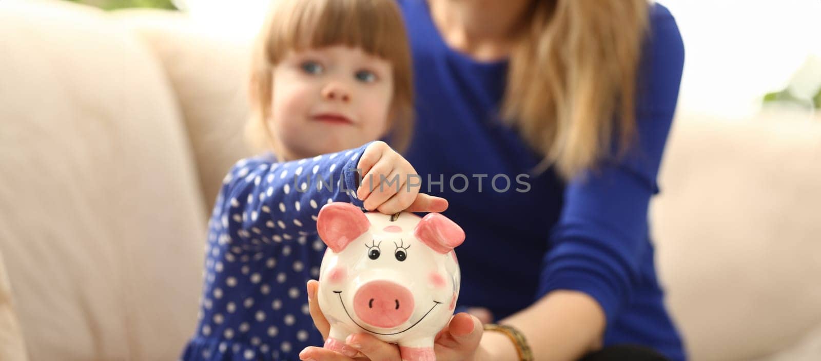 Child little girl arm putting coins into piggybank by kuprevich