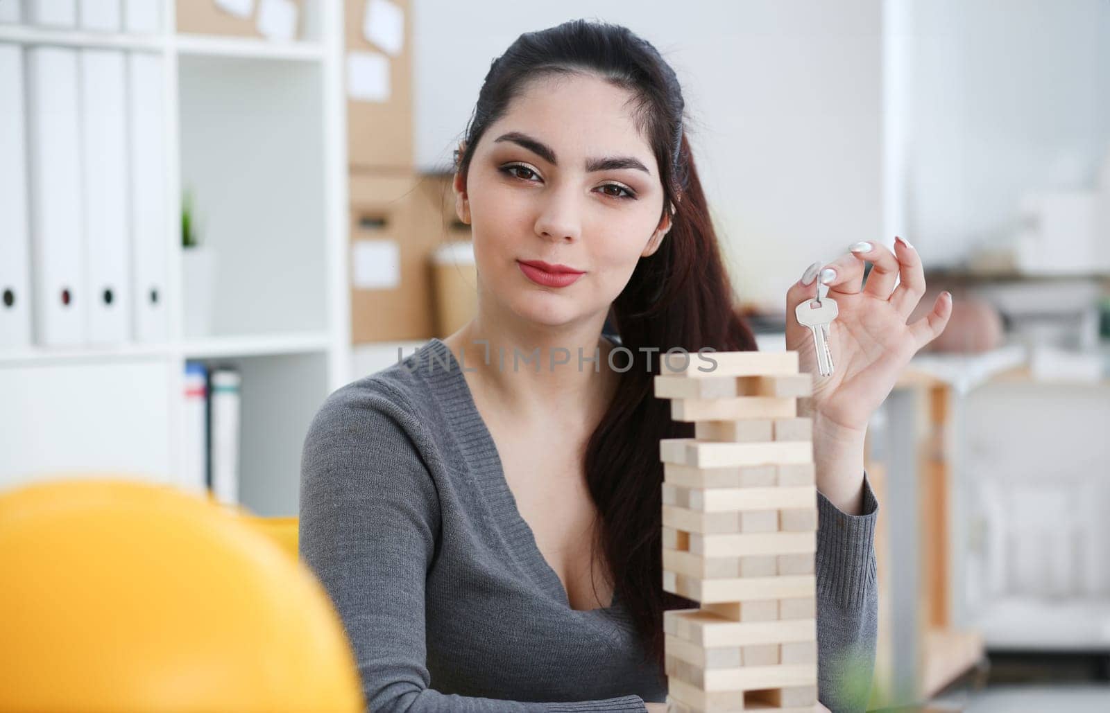 Smiling woman holds the key to the lock in the hand against the backdrop of the toy house sale purchase lease concept real estate services on the market.