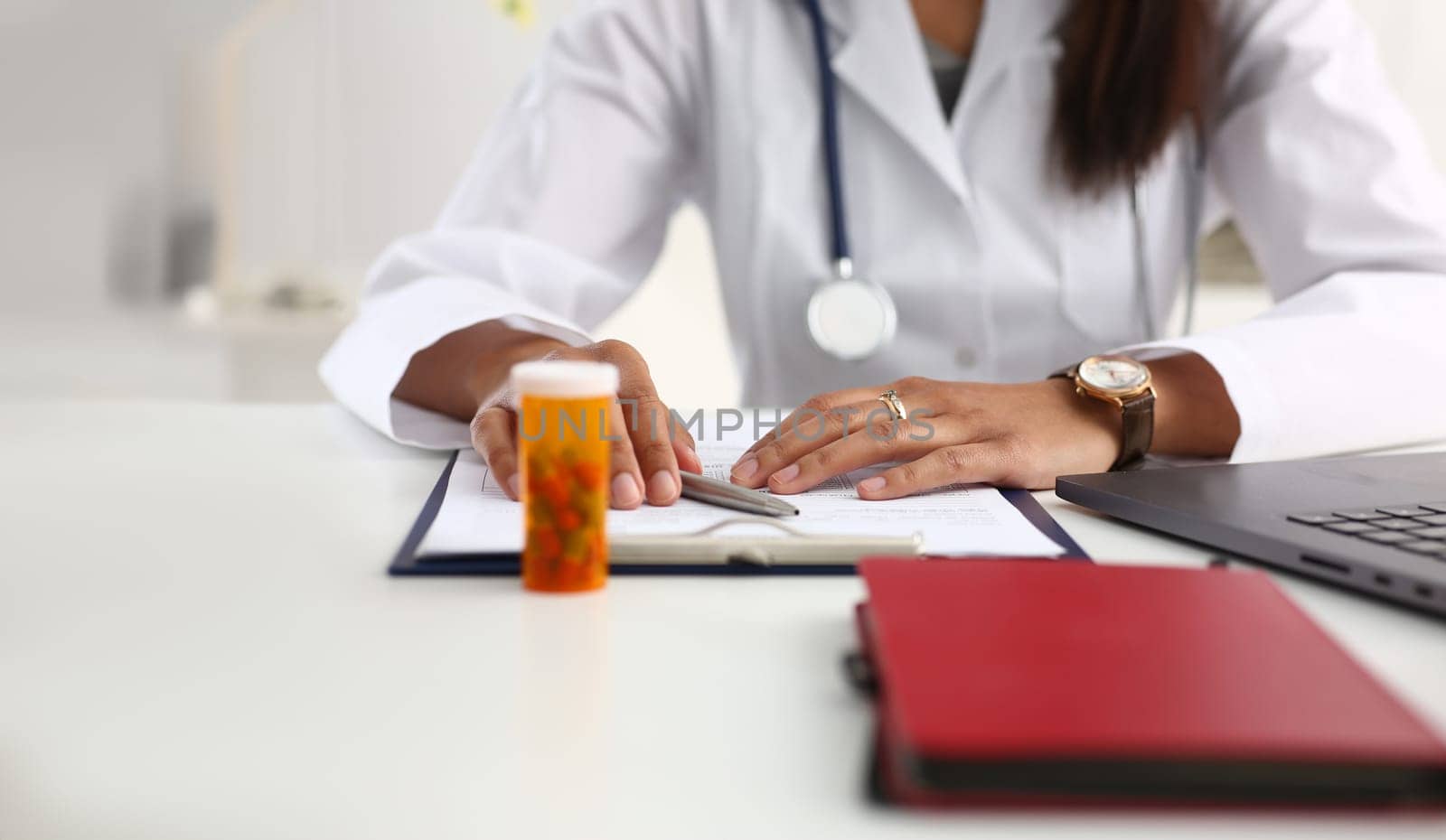 Female black medicine doctor hand hold jar of pills and write prescription to patient at worktable. Panacea and life save, prescribing treatment legal drug store concept. Empty form ready to be used