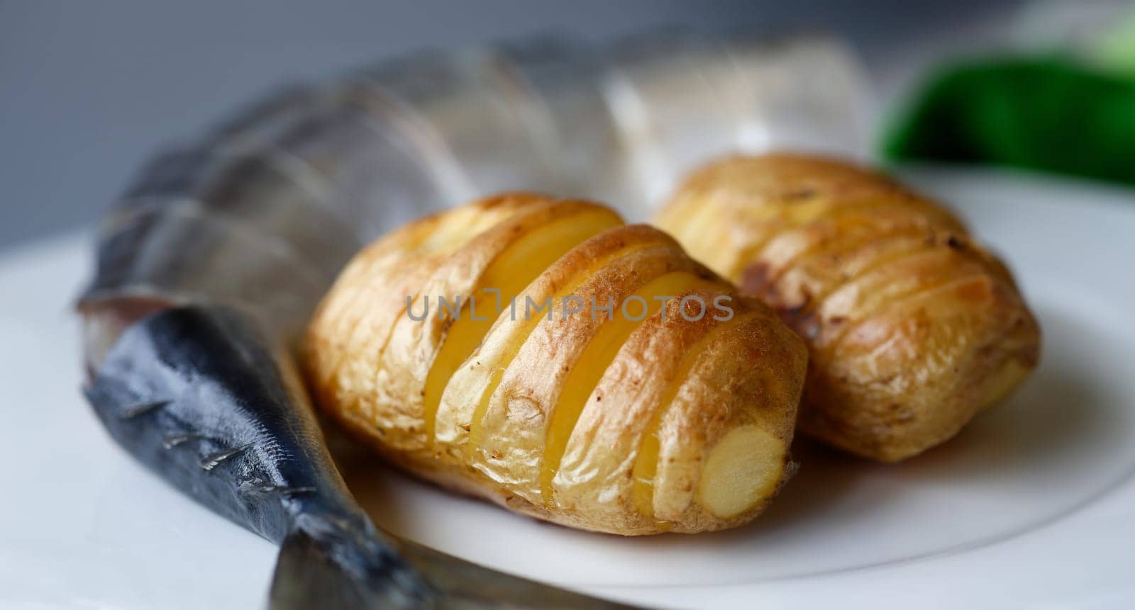 Baked golden potatoes with herring mackerel fish on a white plate. Traditional dish of English cuisine chips and fish