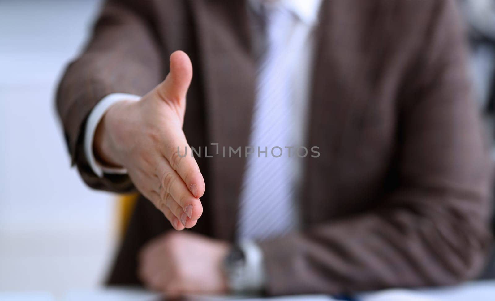 Man in suit and tie give hand as hello in office closeup. Friend welcome mediation offer positive introduction thanks gesture summit participate approval motivation male arm strike bargain