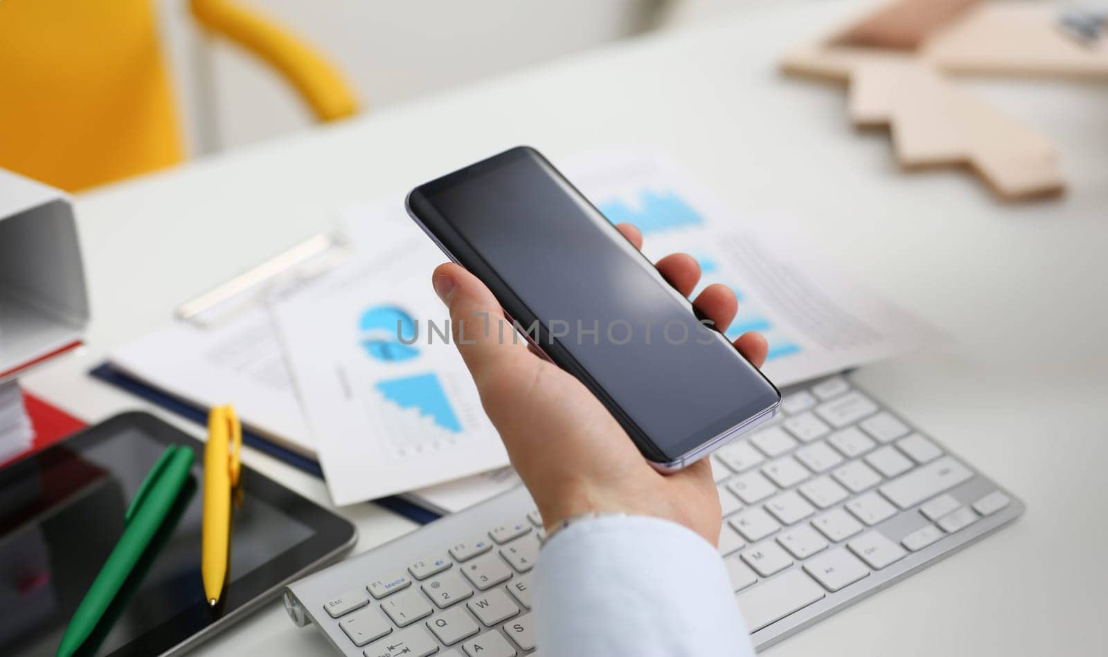 A businessman holds a new smartphone in his hand The mobile application market shows a display you can insert your image for advertising or financial statistics.