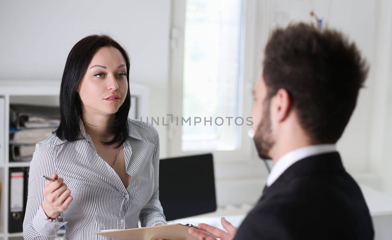 pretty brunette woman and man argue in office sitting at table