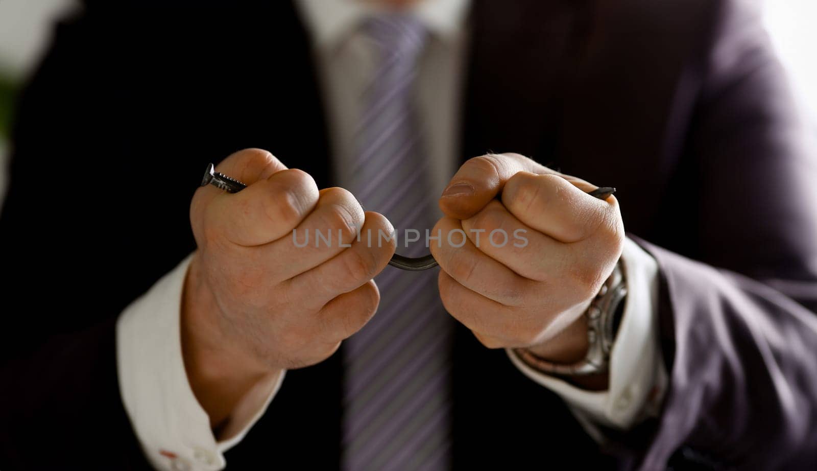 Man in suit and tie bend nail with arms closeup no limit energy easy problem solve issue superman help pressure concept