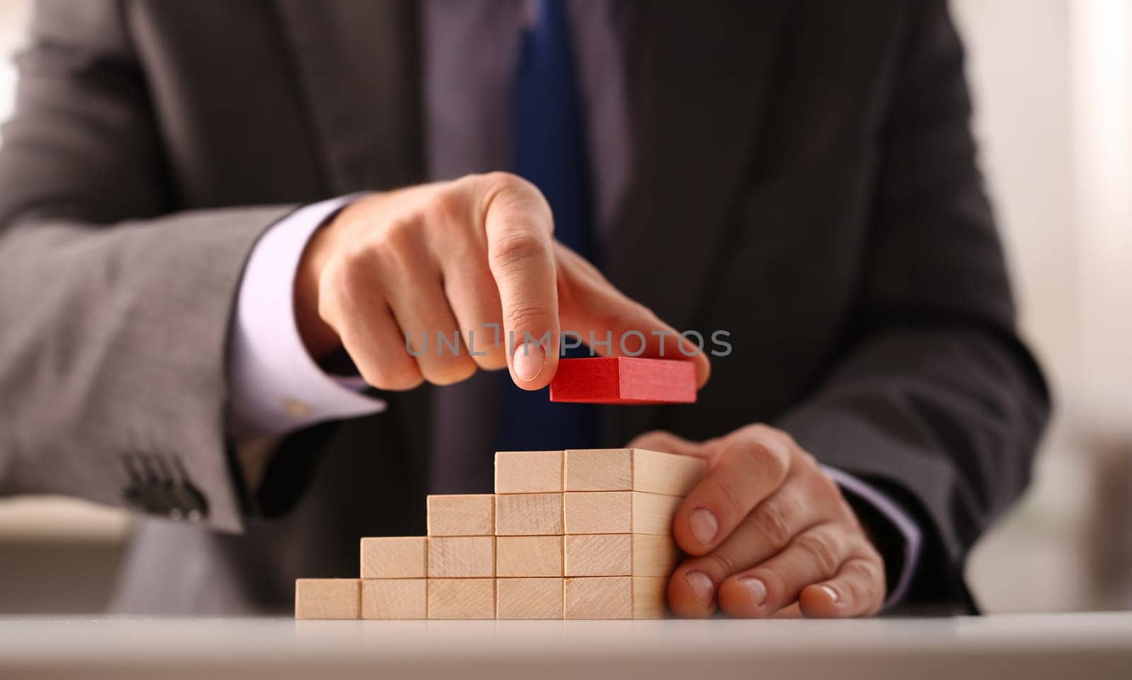 Male hand holds red wood block of stair by kuprevich